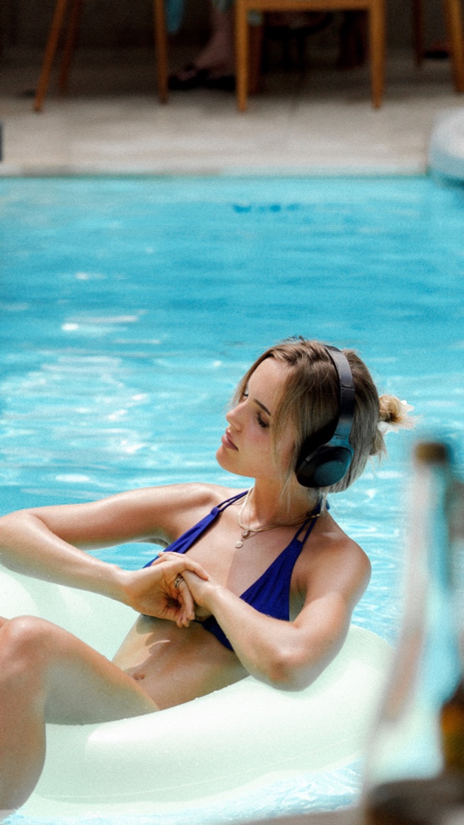 Guest in headphones floating on a pool ring at Mowie's