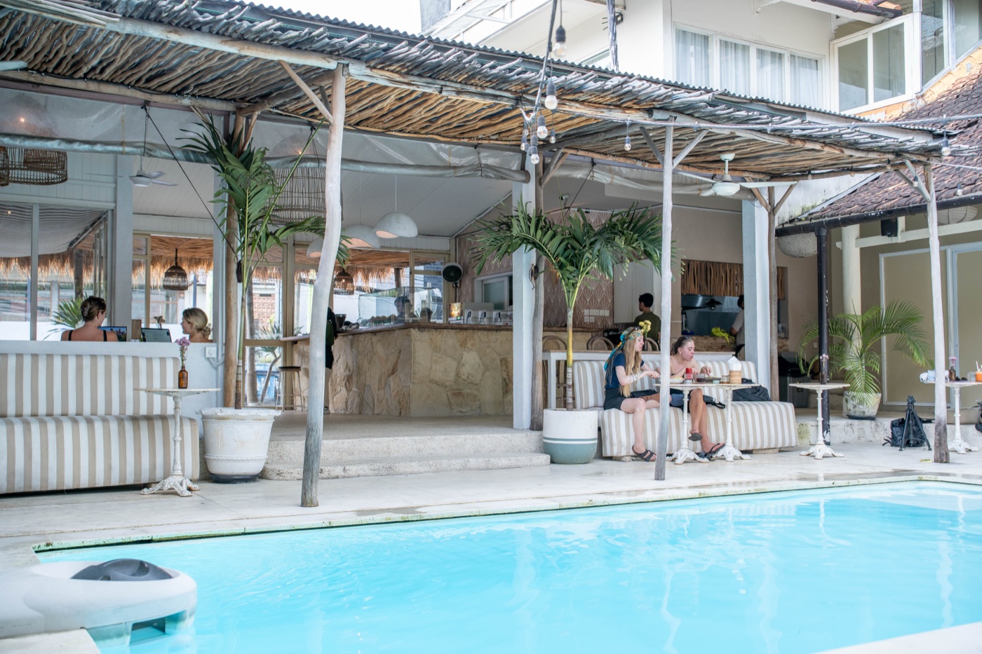Mowie's Bali pool deck with thatched roof, dining banquettes, and bar