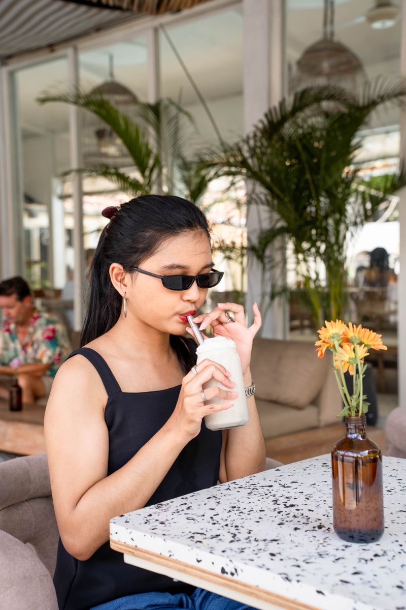 Guest sipping a house drink at a terrazzo table at Mowie's